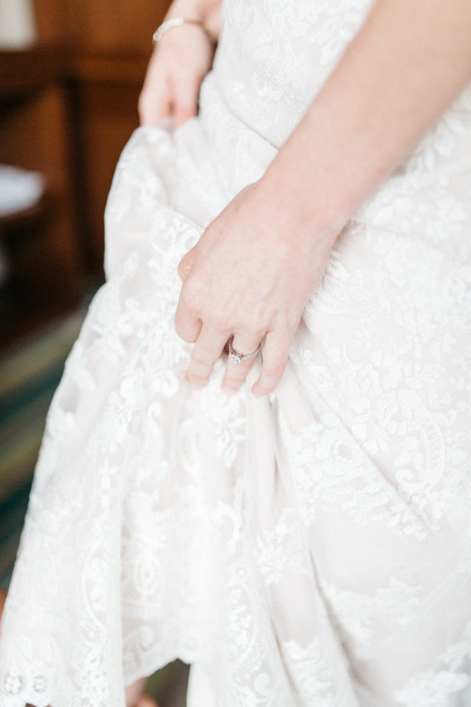 bride holding dress with engagement ring