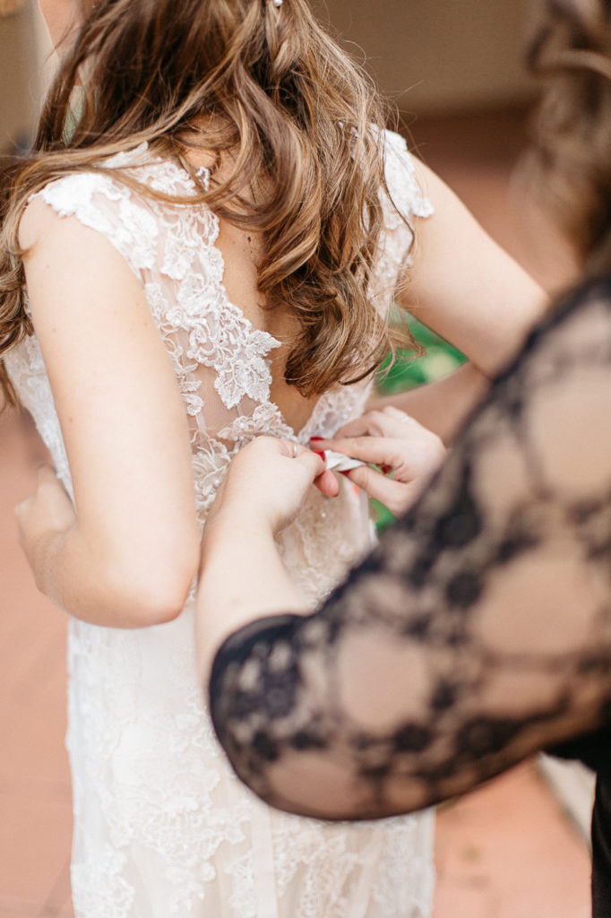Bride being buttoned into bridal gown mission inn wedding