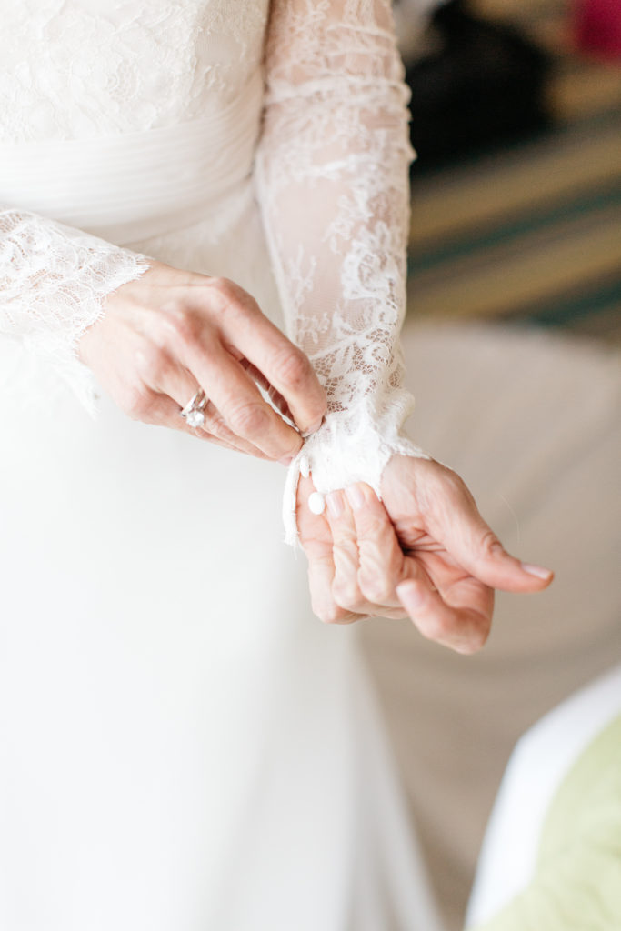 bride buttoning her lace sleeves at the alfond inn