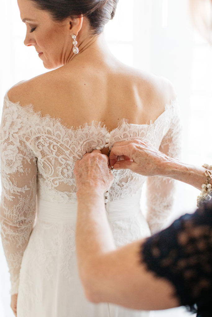 bride being buttoned into dress at the alfond inn