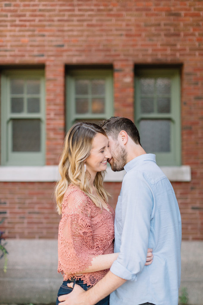 couple standing in front of brick building and holding each other for Chicago, Illinois engagement session
