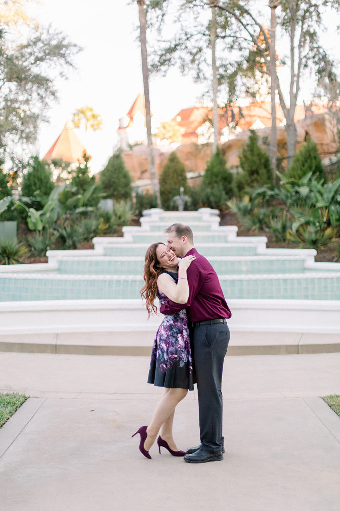 couple giggle together at Disney's grand Floridian resort for engagement session photos